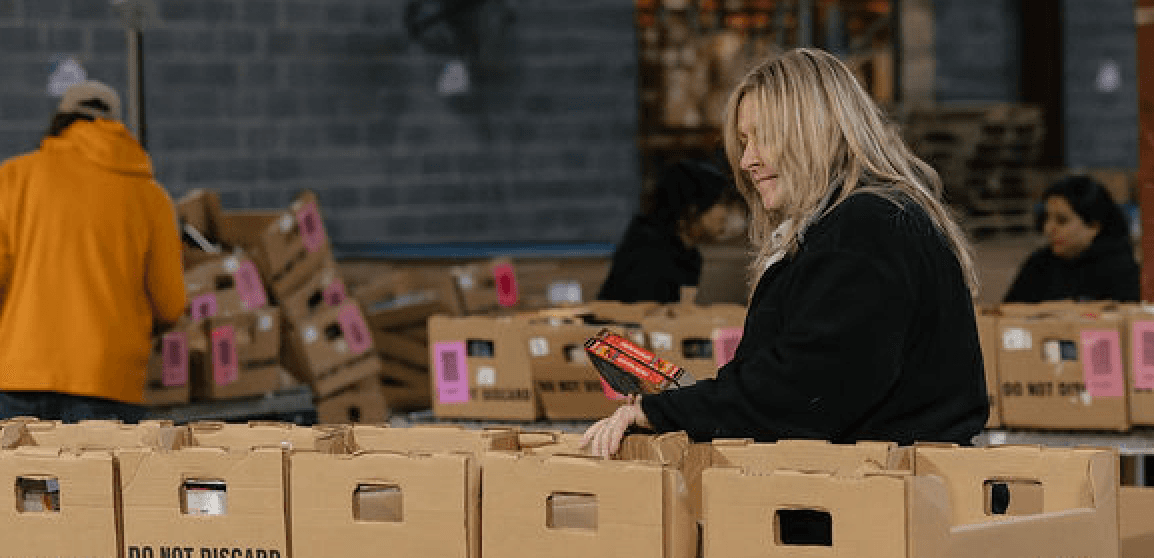 Woman sorting books between boxes in ABC warehouse