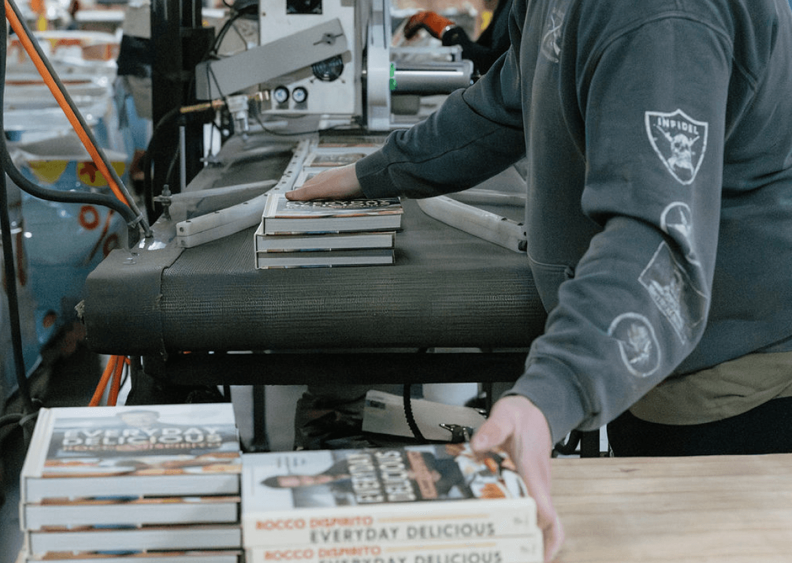 Image of someone sorting books off a conveyer onto a table in the ABC warehouse