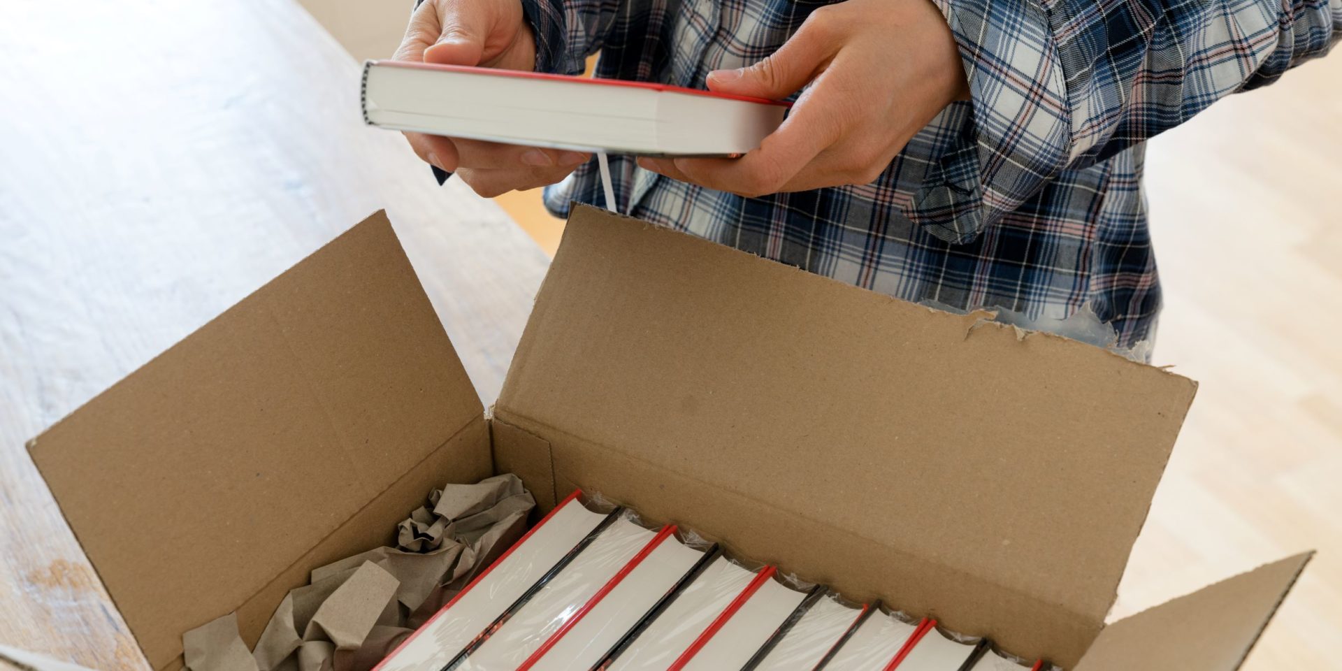 Man opening a delivery box of bulk discounted books.