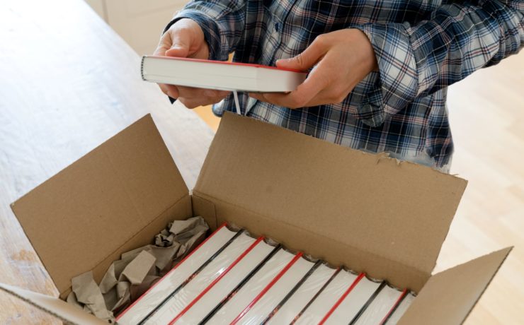 Man opening a delivery box of bulk discounted books.
