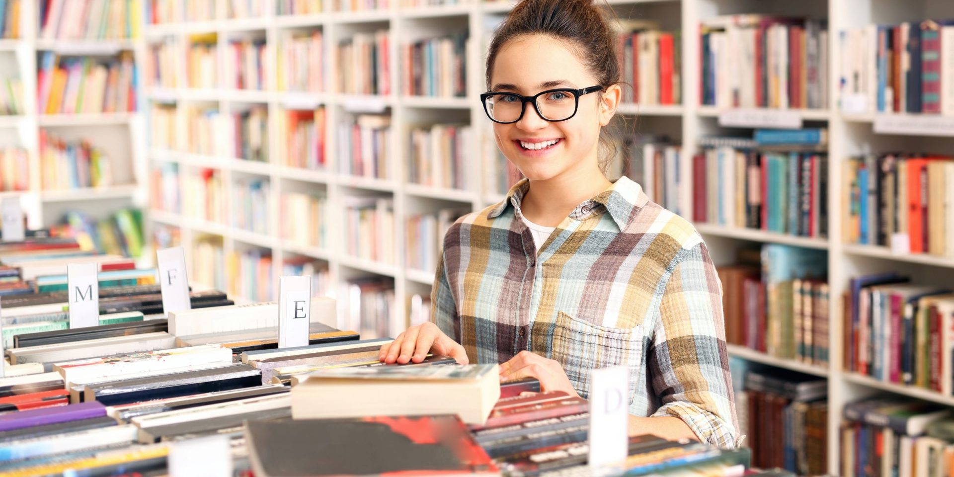 Teenager looking through young adult books at a book store.
