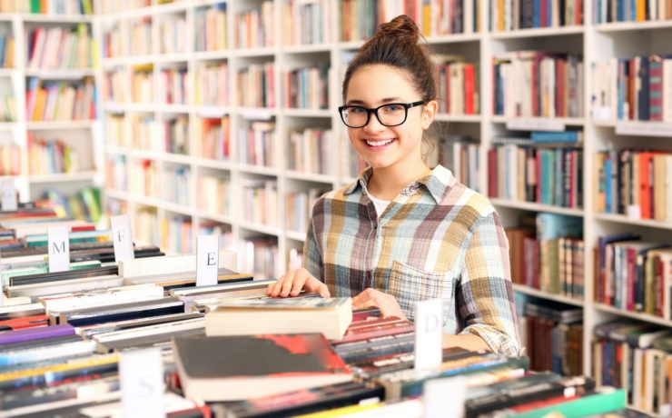 Teenager looking through young adult books at a book store.
