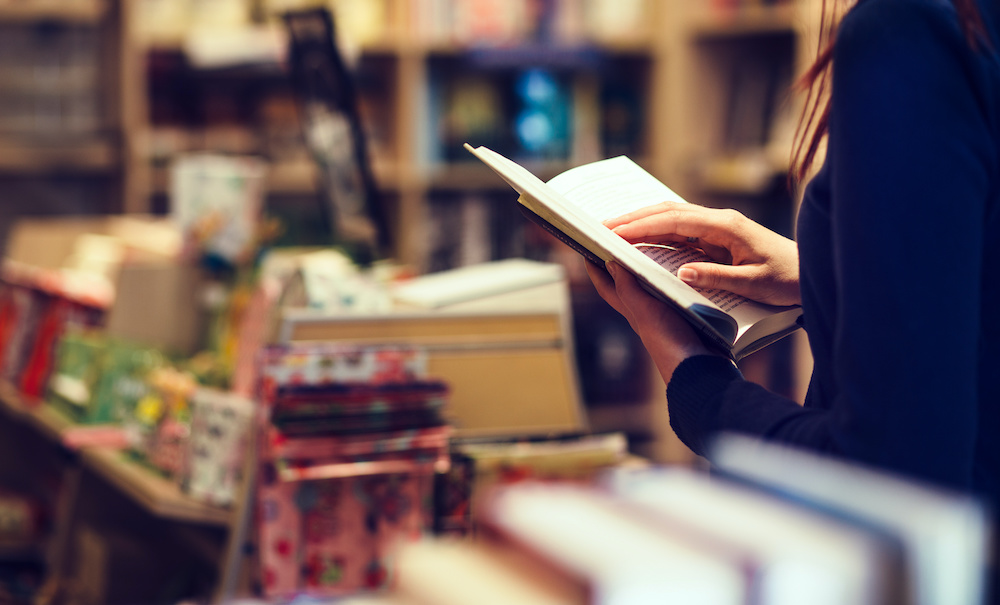 Woman reading a novel in a boutique's book section.