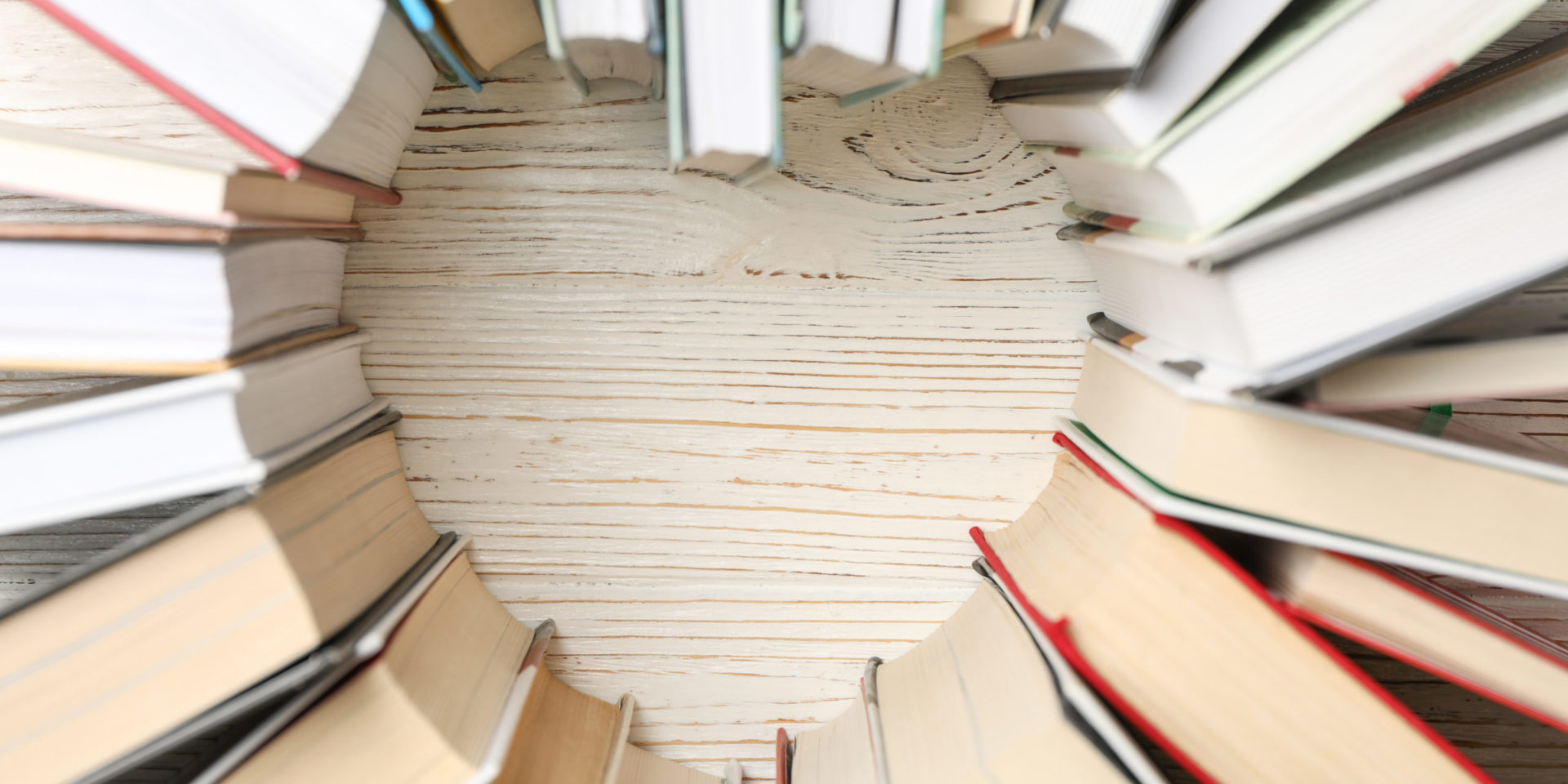 Heart made of books on white wooden rustic background